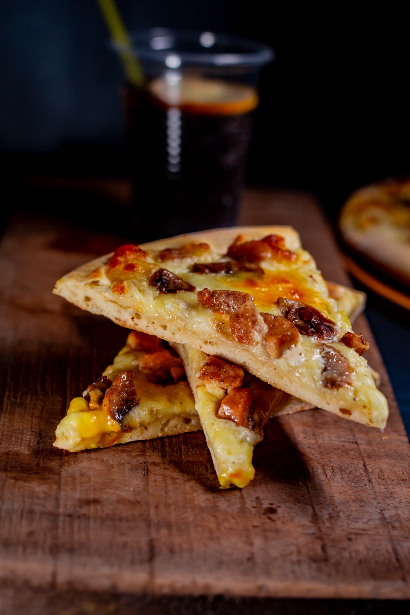 Slices of pizza with melted cheese and toppings on a wooden board