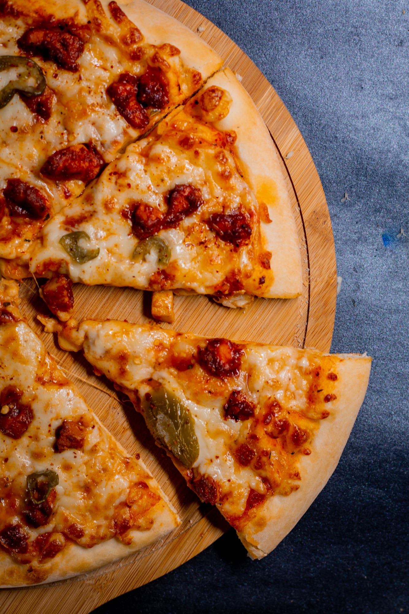 Slices of pizza on a wooden board against a blue background