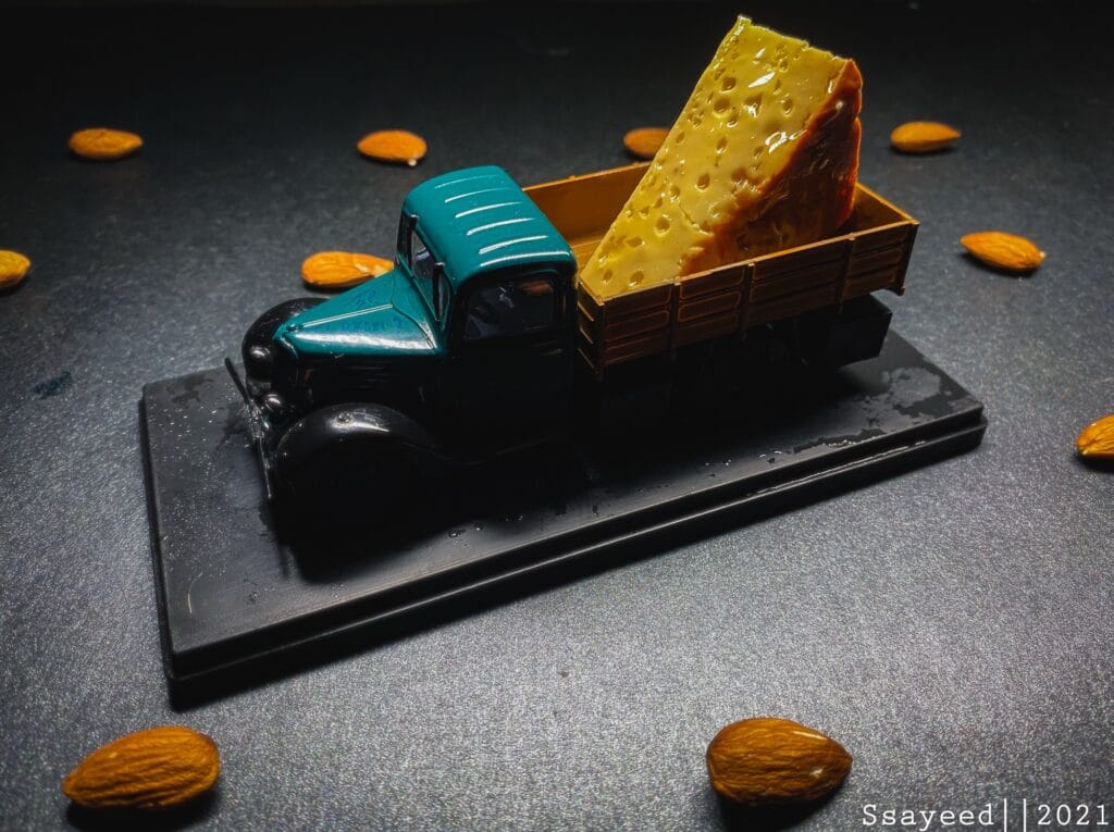 A photograph of a cheese over a toy truck