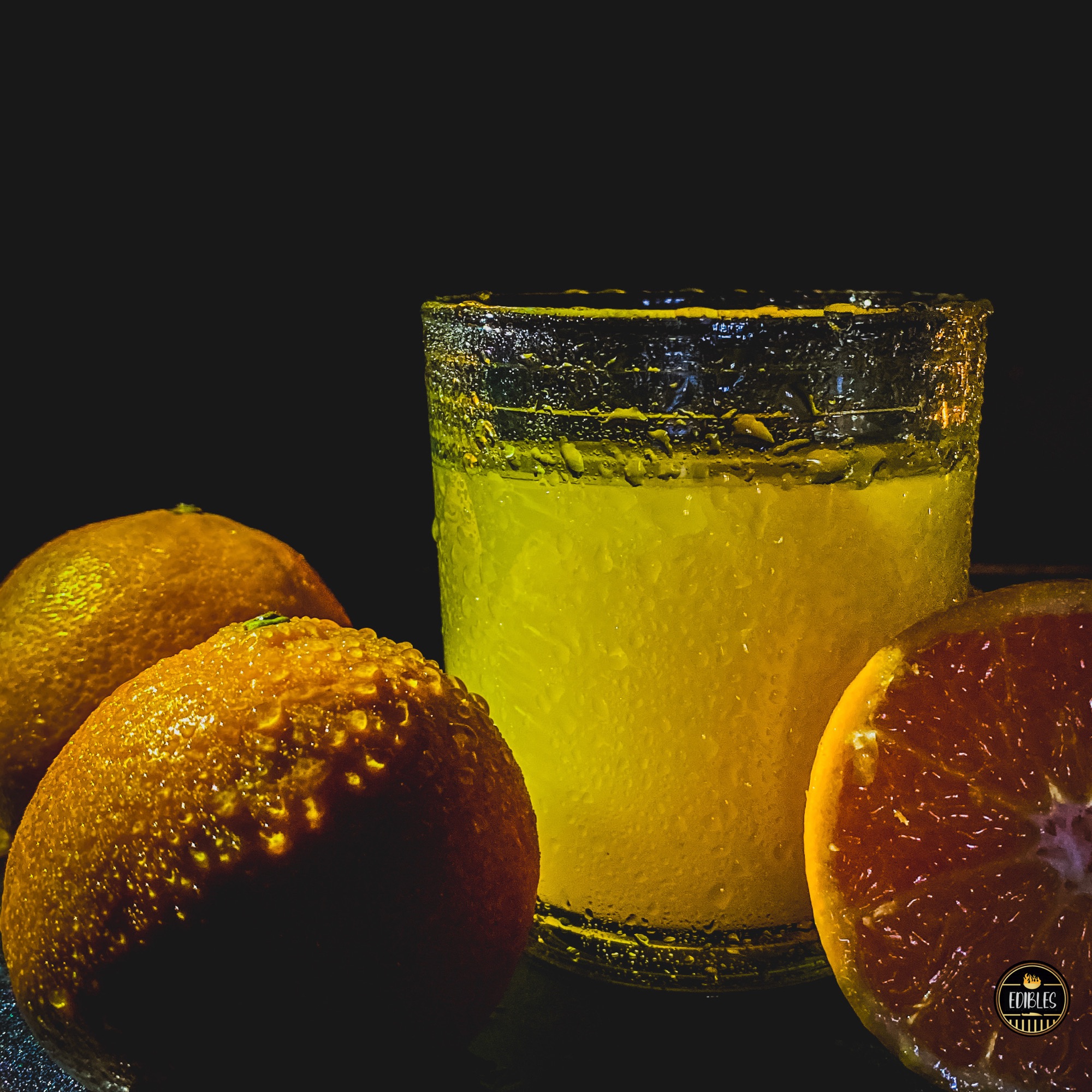 Glass of orange juice styled with donuts and pastries on a dark background