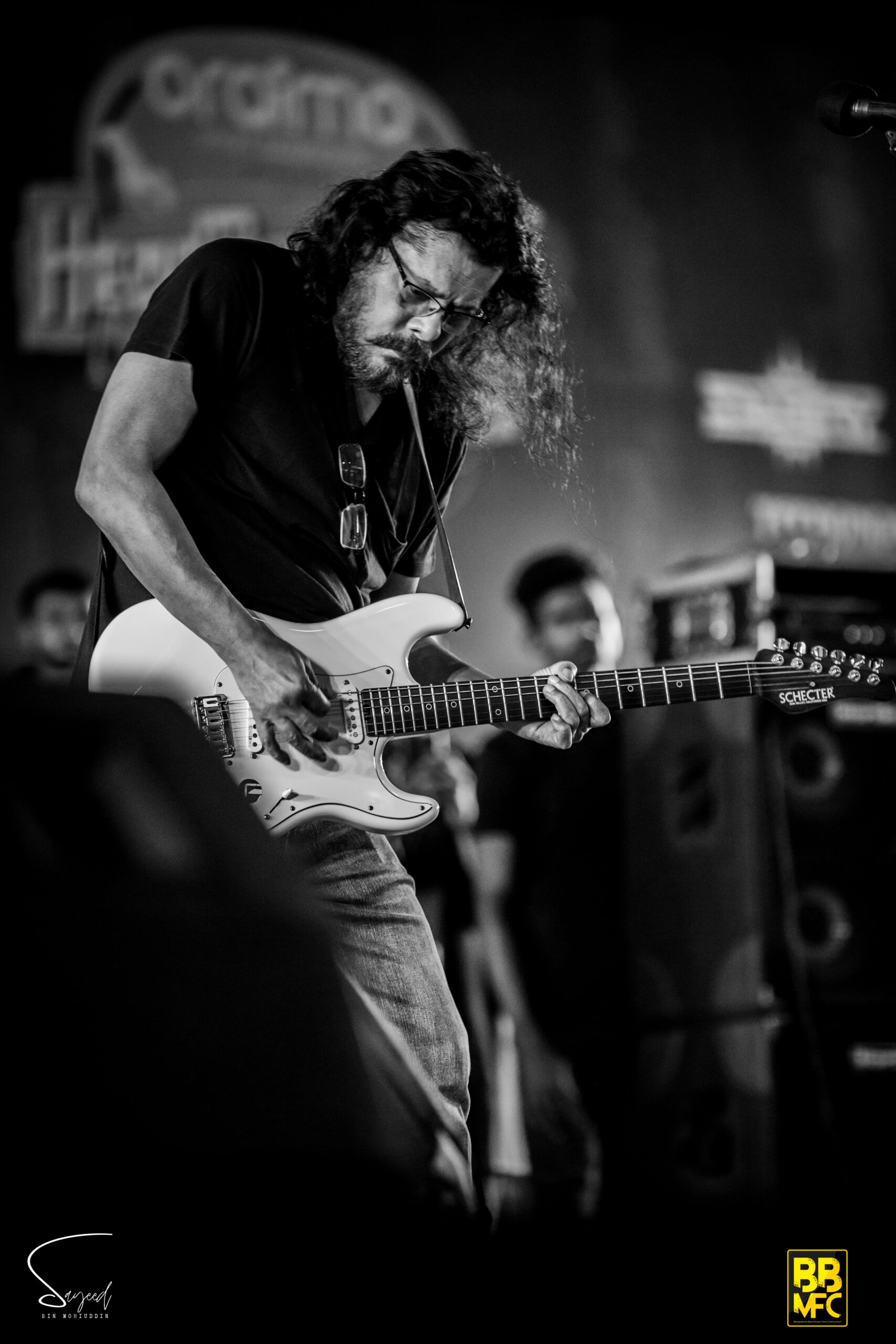 Guitarist with flowing hair leaning into a solo on a white Stratocaster, black-and-white shot at a Dhaka concert — Sayeed BM