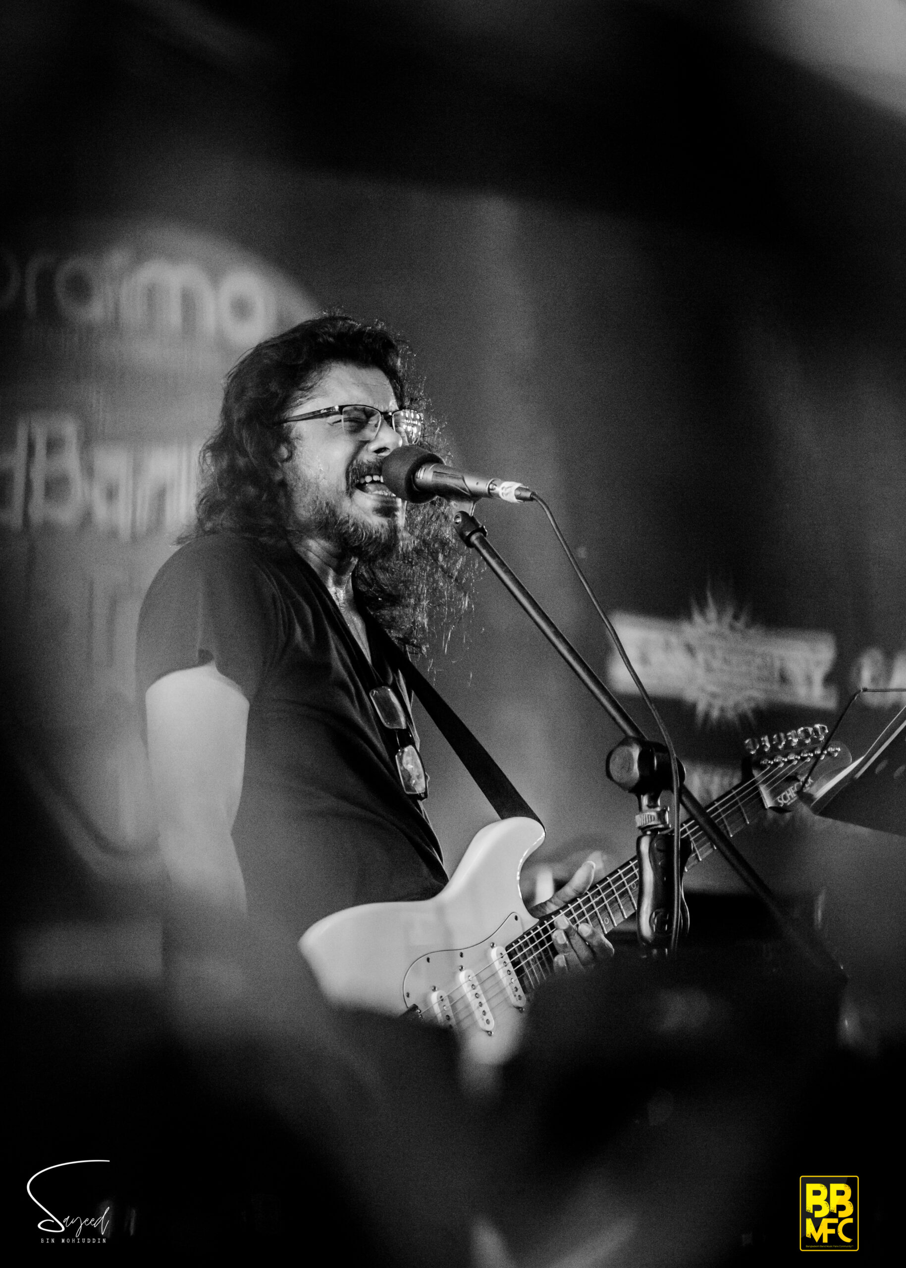 Long-haired guitarist singing passionately into the mic, black-and-white shot from a Shironamhin concert in Dhaka — Sayeed BM