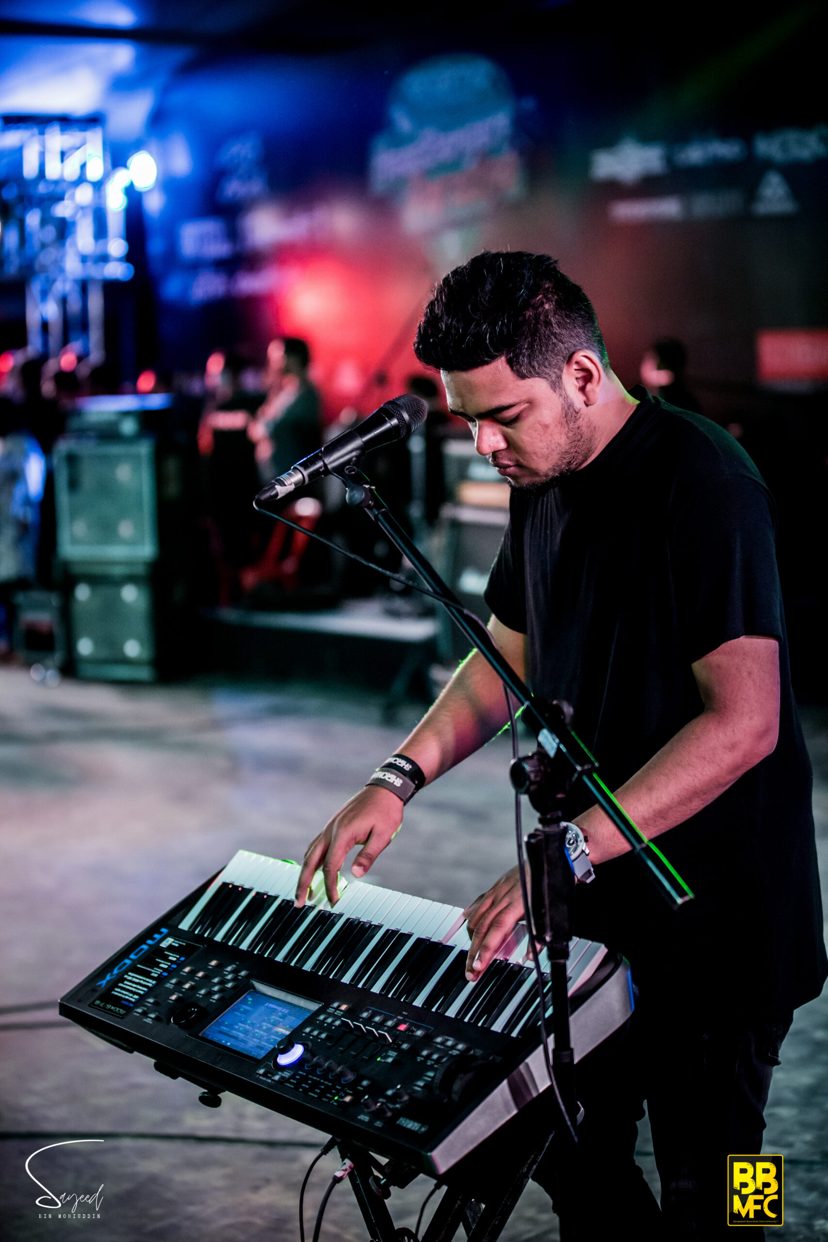 Keyboardist leaning over his synth, focused on the keys at a live concert in Dhaka — Sayeed BM