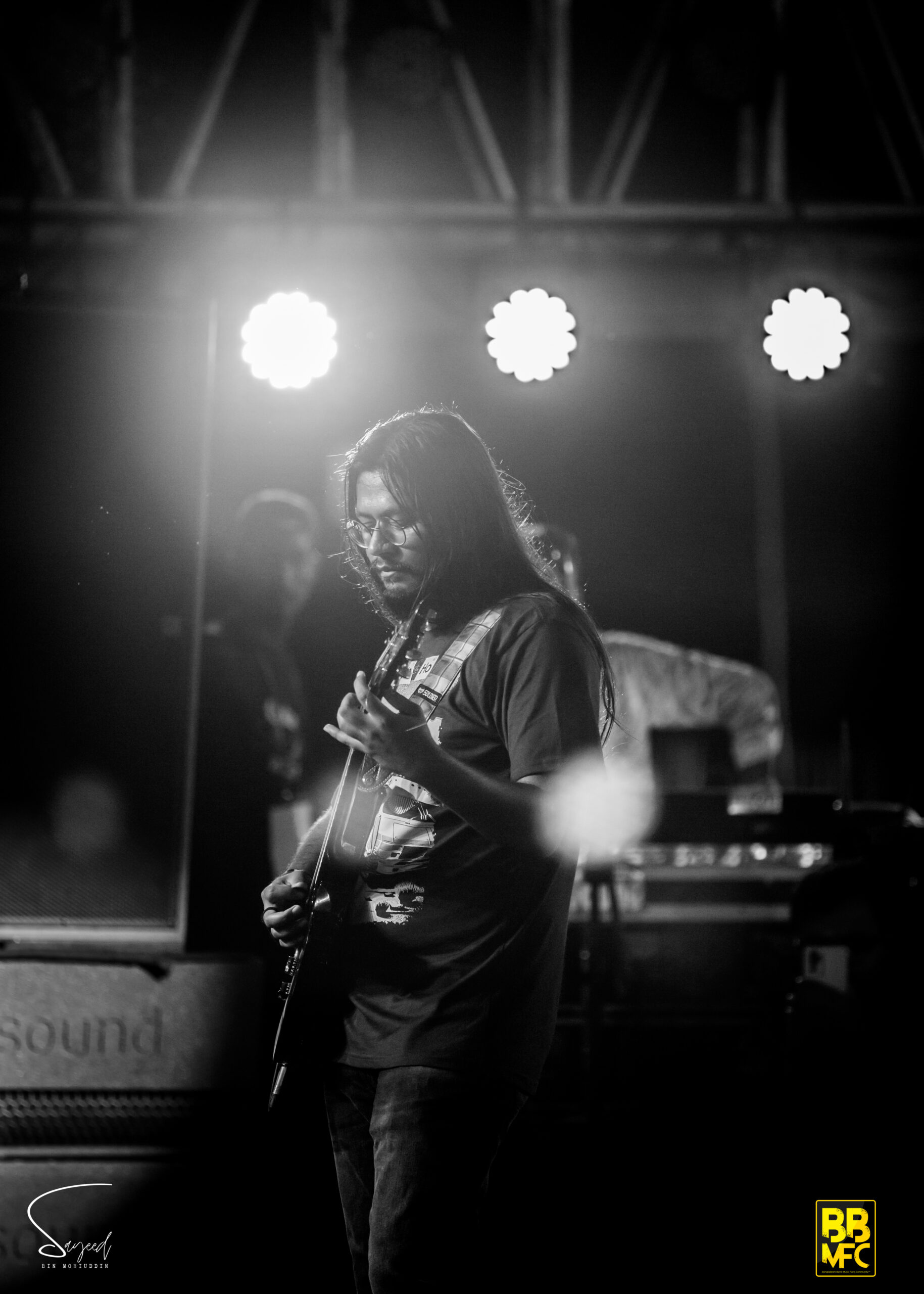Guitarist silhouetted against bright stage lights, black-and-white concert photo from Dhaka — Sayeed BM
