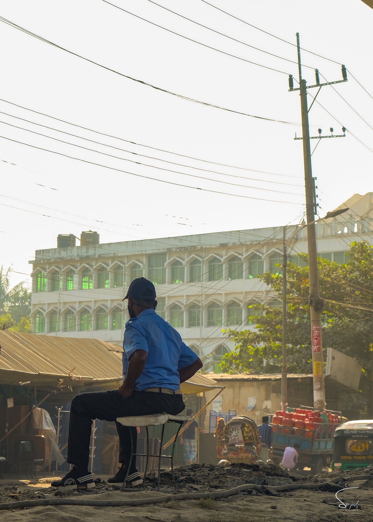 Woman in black abaya walking past a mosque exterior, Dhaka street scene