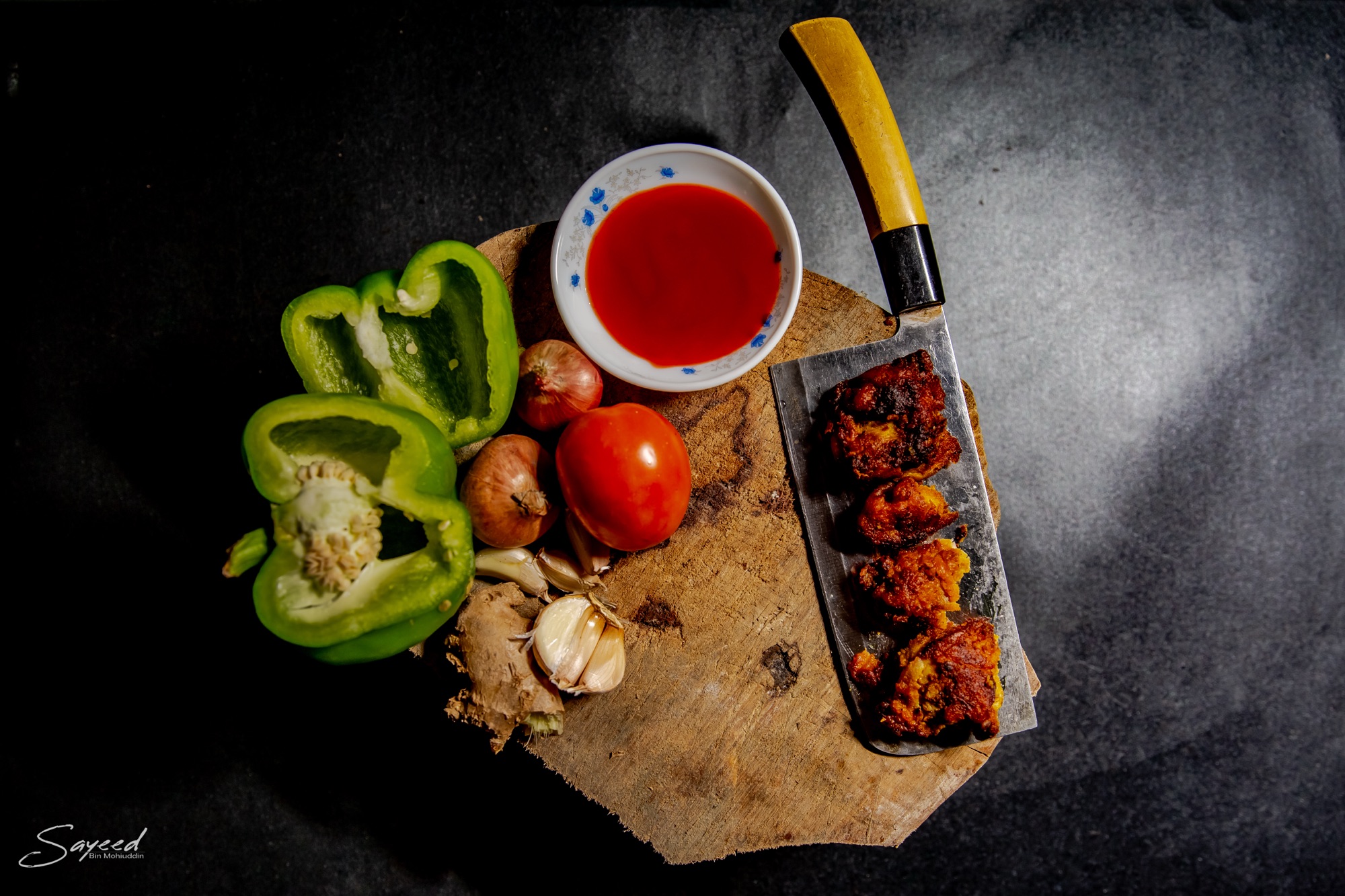 Overhead board of grilled kebab skewers with peppers, tomato and chili dip