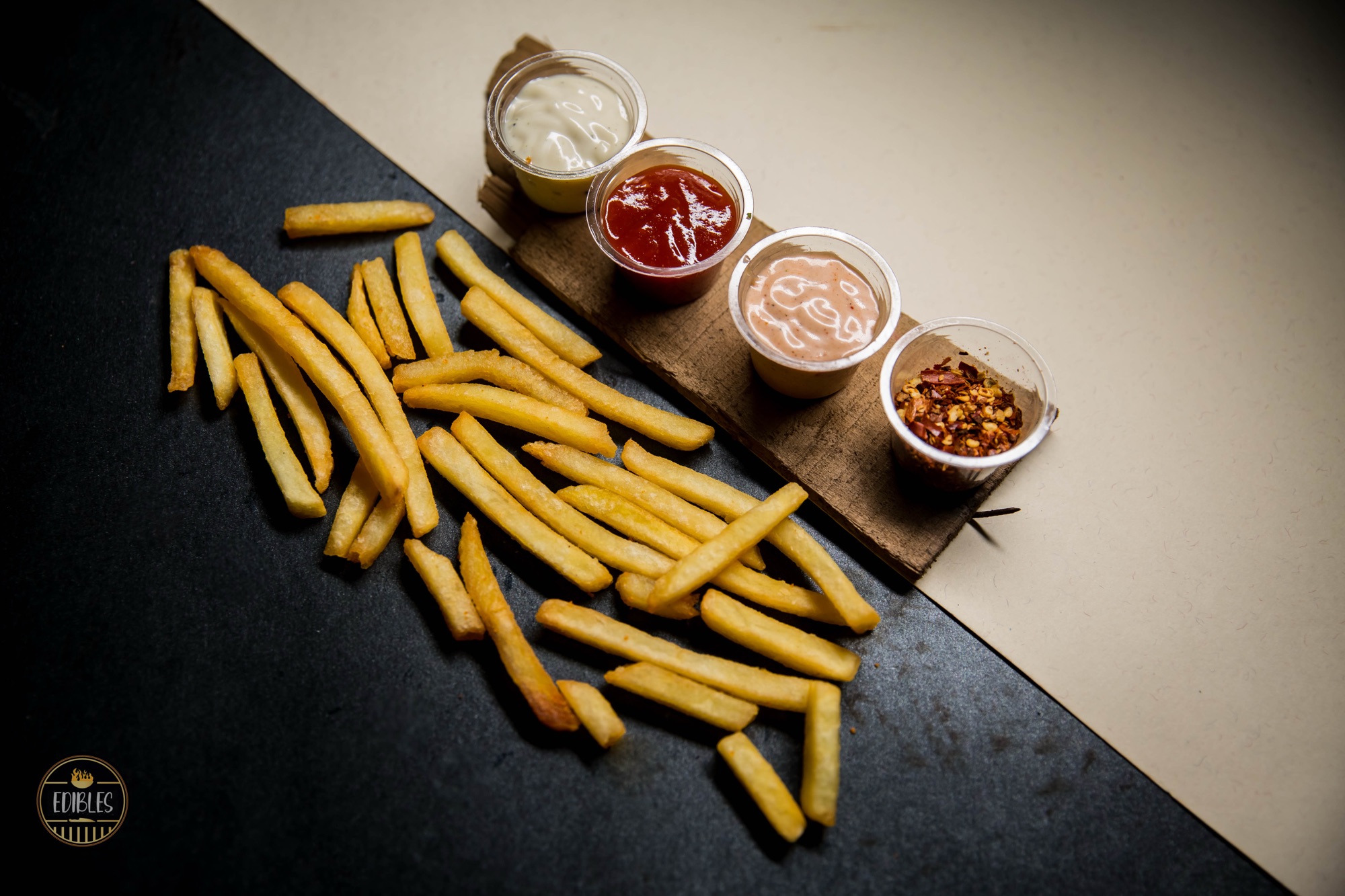 Golden fries with three dipping sauces arranged on a wooden board