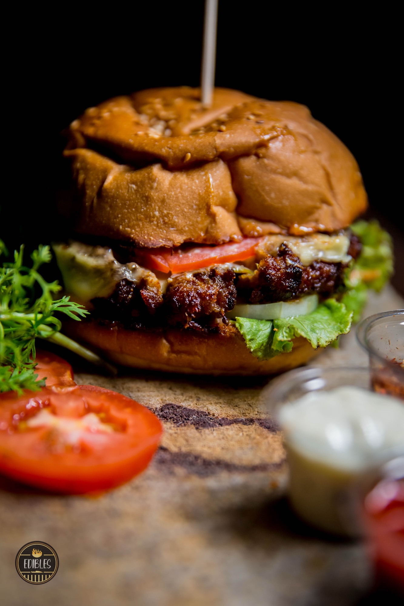 Loaded burger with fresh herbs and sliced tomato, close-up detail shot