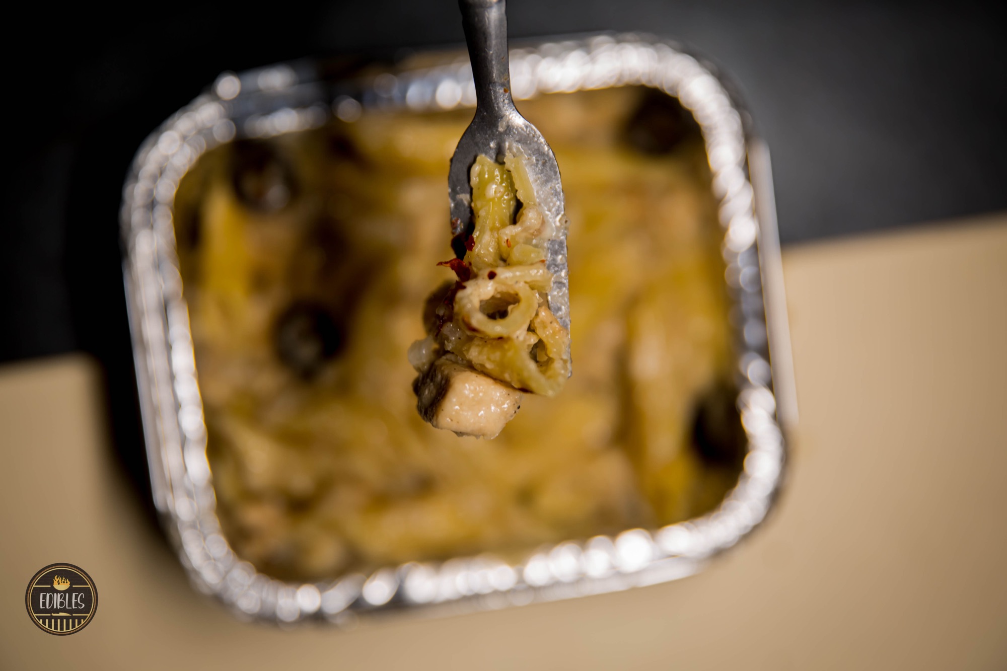 Tongs lifting golden onion rings from a foil tray with steam rising — food photography by Sayeed BM