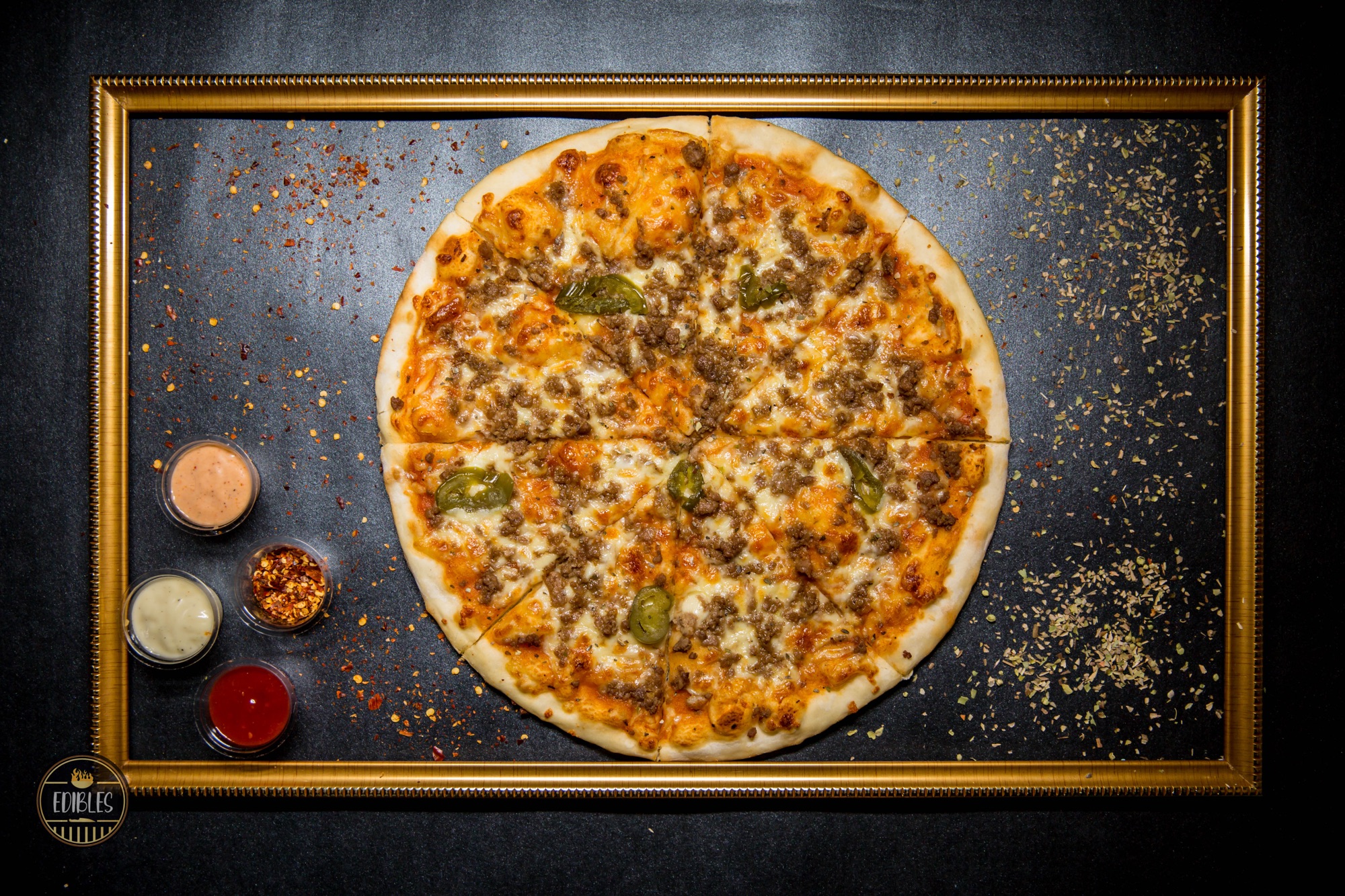 Overhead shot of a whole cheese and vegetable pizza on a dark slate background