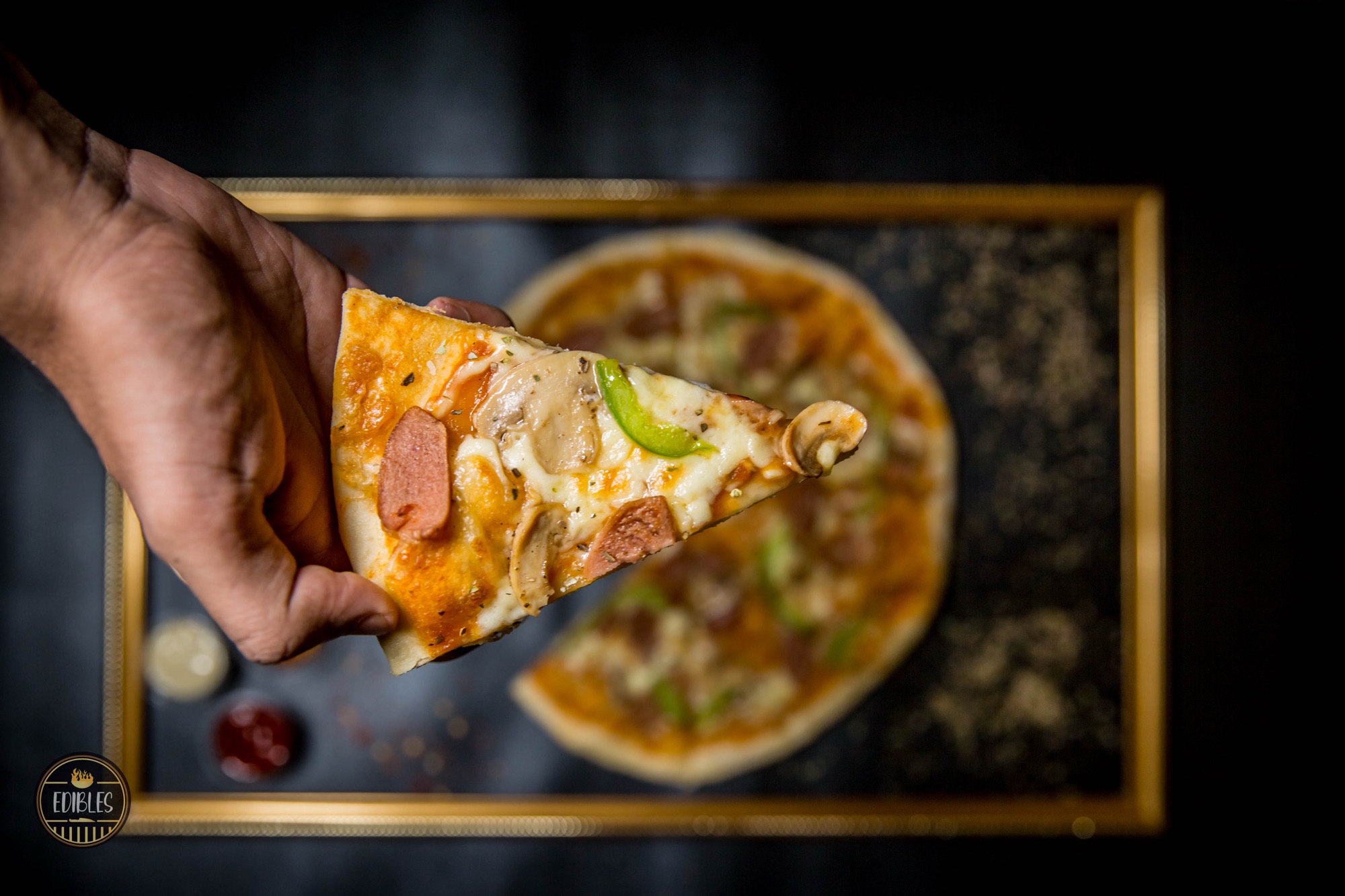 Hand holding a slice of pepperoni and pepper pizza pulled from the pie