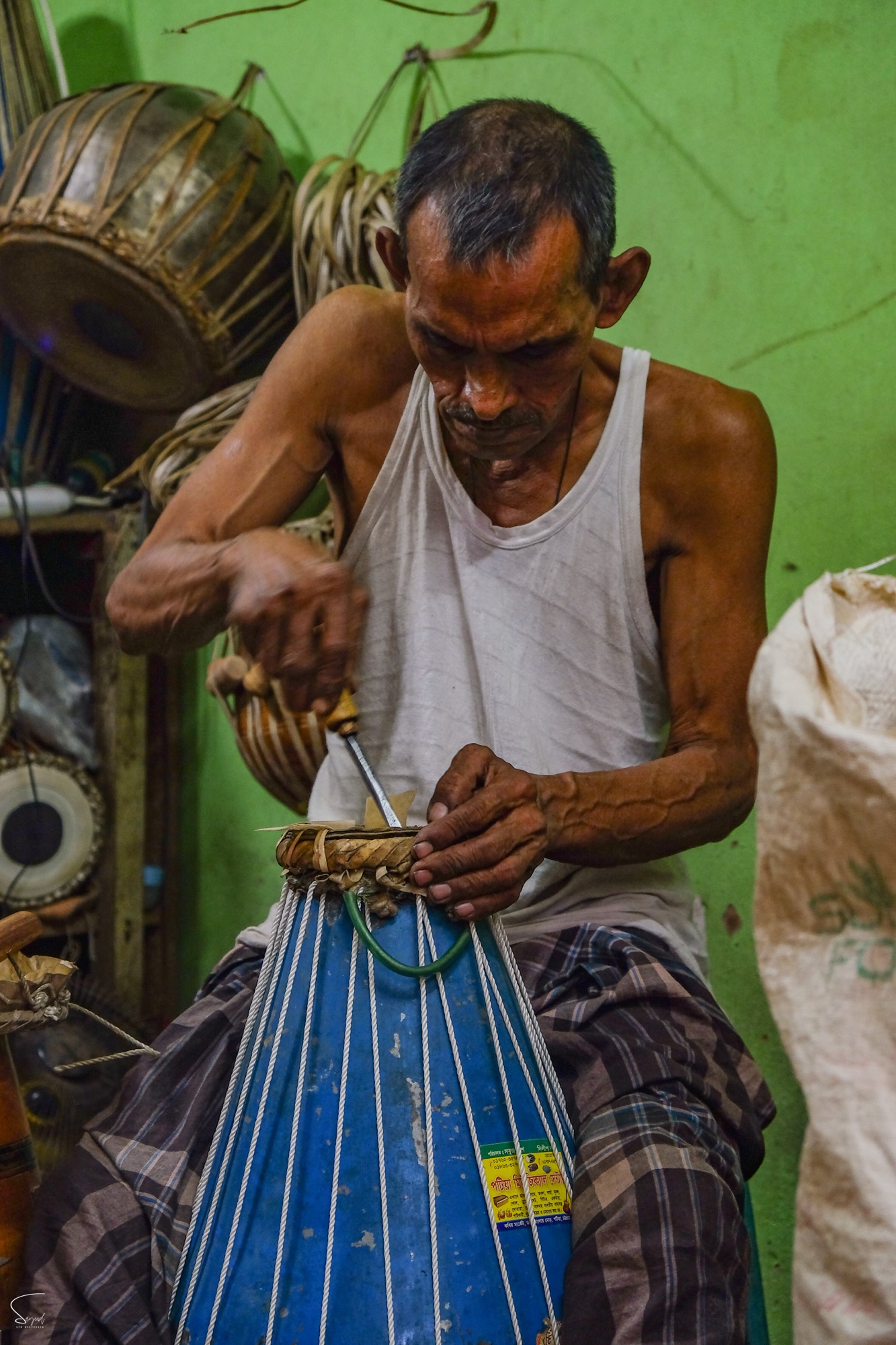Close-up of elderly craftsman's hands at work, weaving or stitching, Dhaka