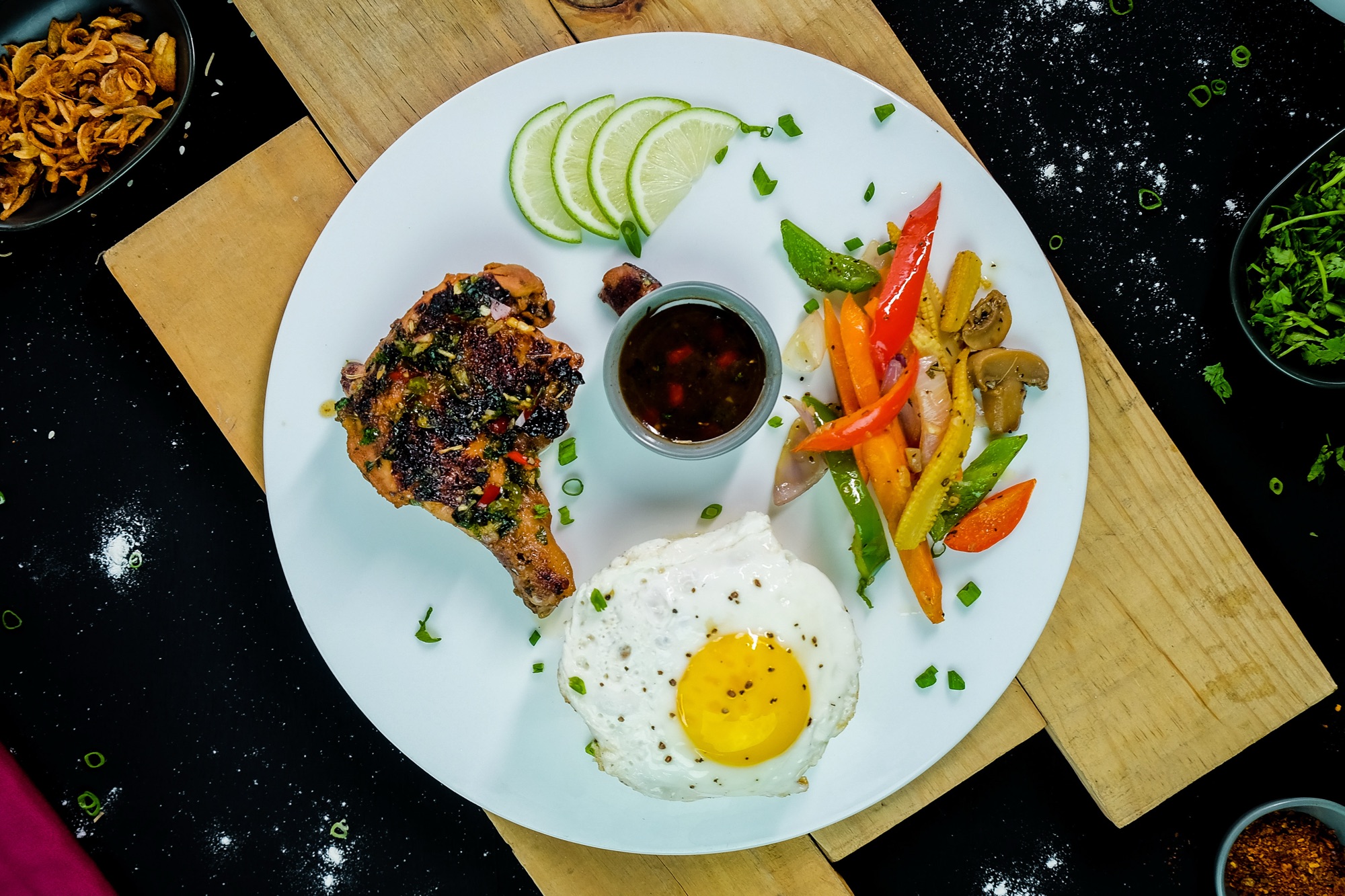 Overhead plate of fried chicken, sunny-side-up egg and sautéed vegetables with dipping sauce