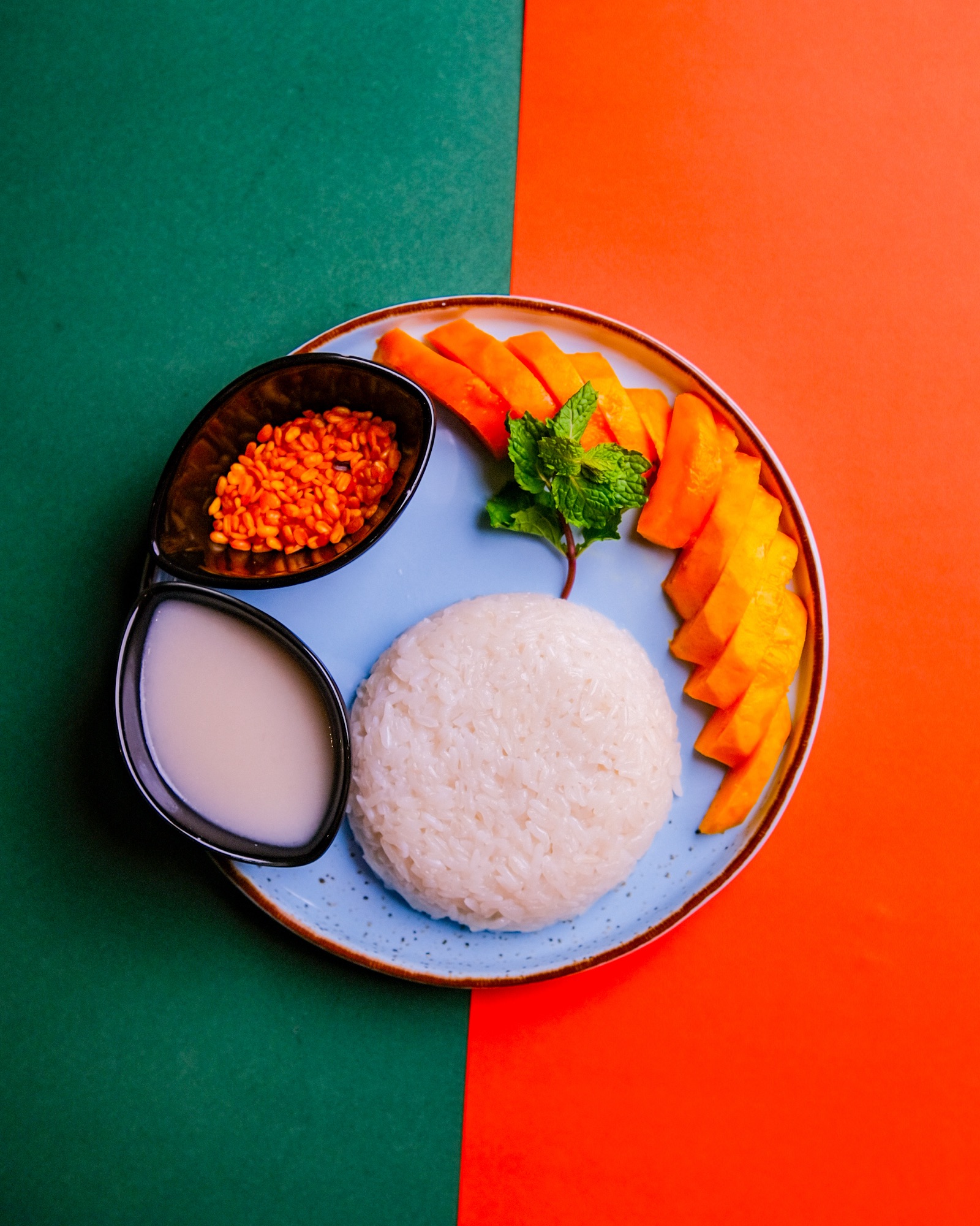 Overhead plate of rice and dumplings styled on a bold split orange and blue background, vibrant food photography by Sayeed BM in Dhaka