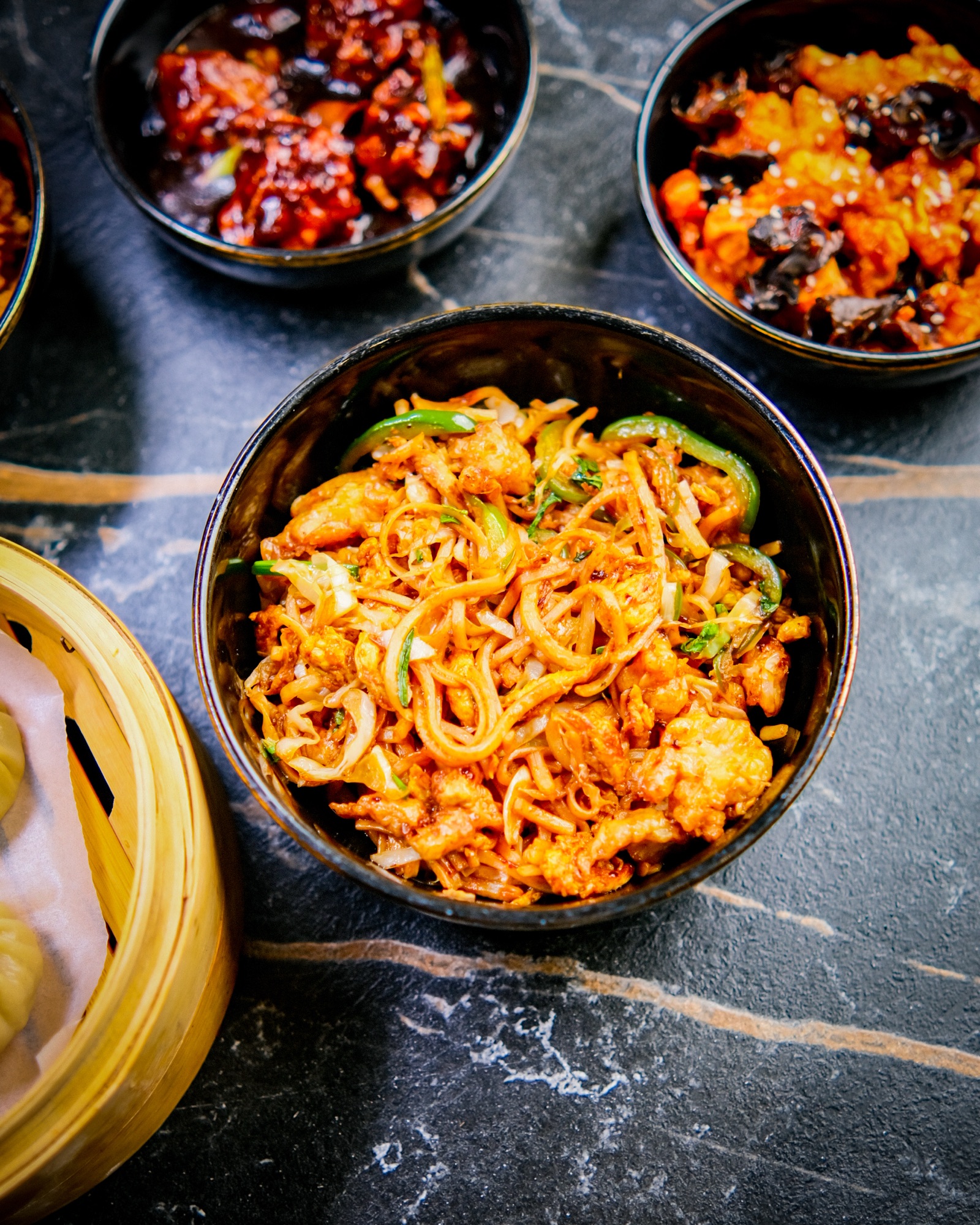 Overhead bowl of stir-fried noodles on a dark background