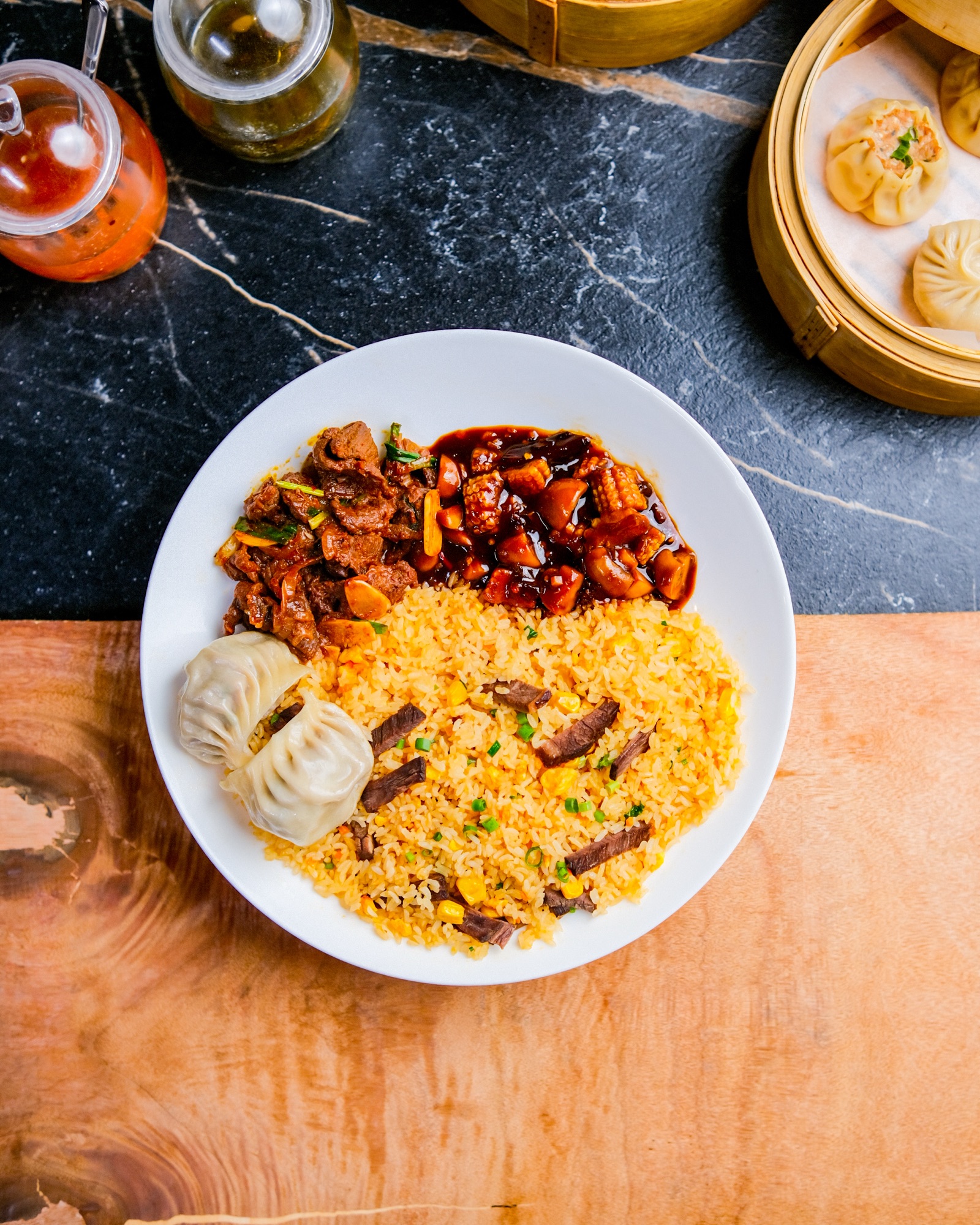 Overhead plate of fried rice with chicken and dumplings on a dark background