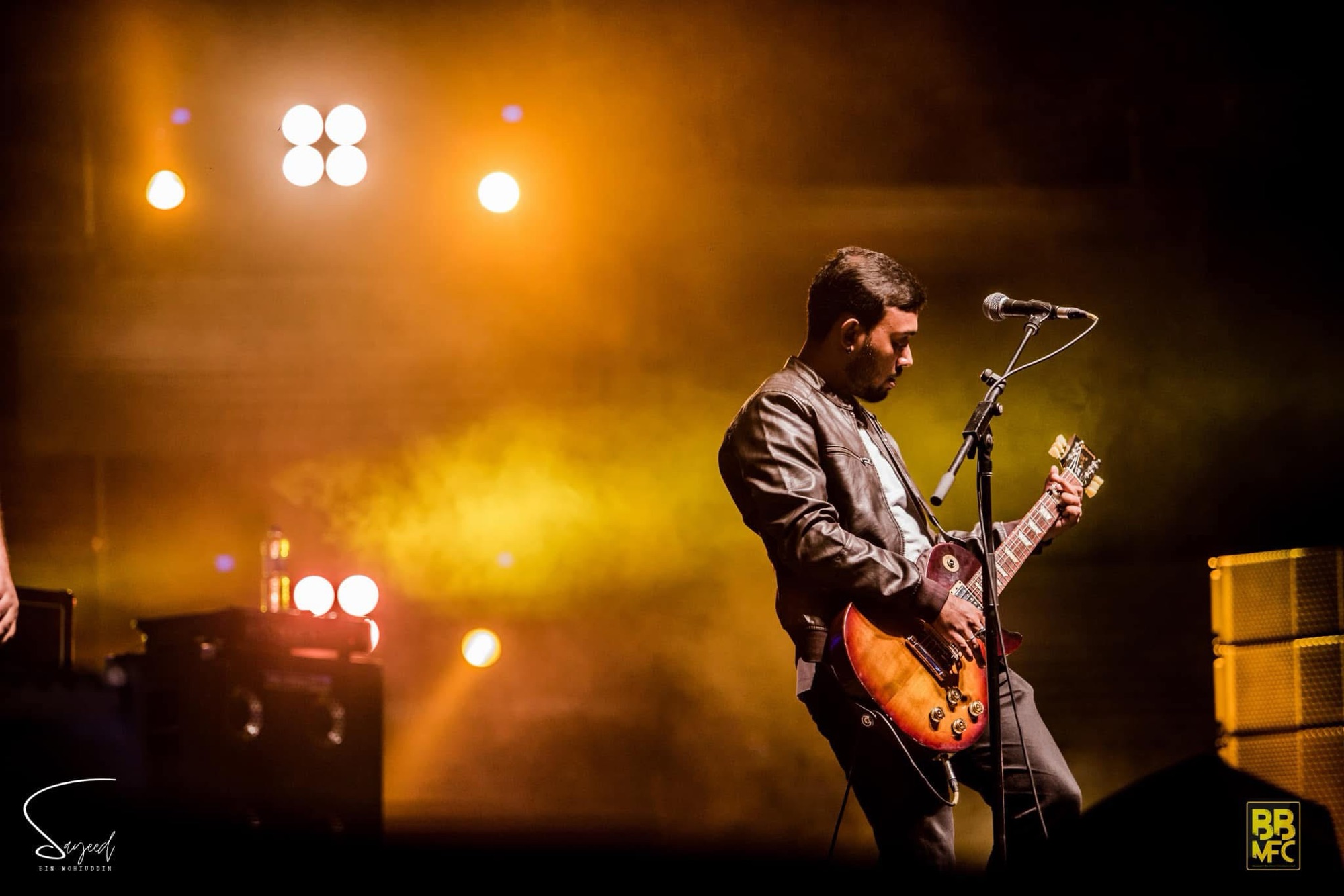 Performer on stage under warm stage light at a Shironamhin concert in Dhaka — Sayeed BM