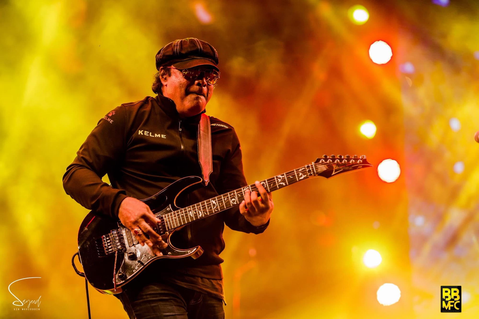 Guitarist performing under warm golden stage light at a Shironamhin concert in Dhaka — Sayeed BM