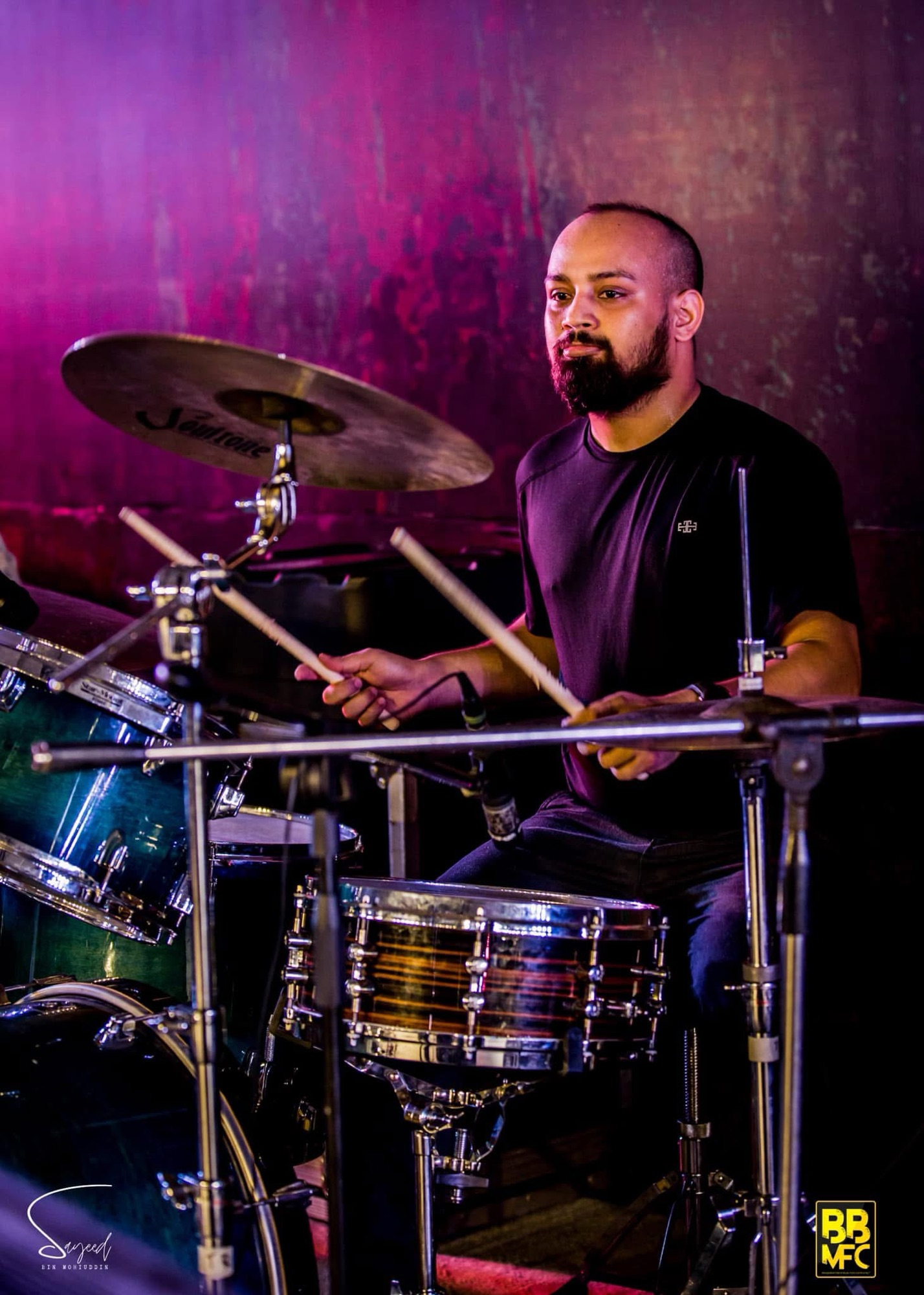 Drummer mid-performance under pink and purple stage light at a Shironamhin concert in Dhaka — Sayeed BM