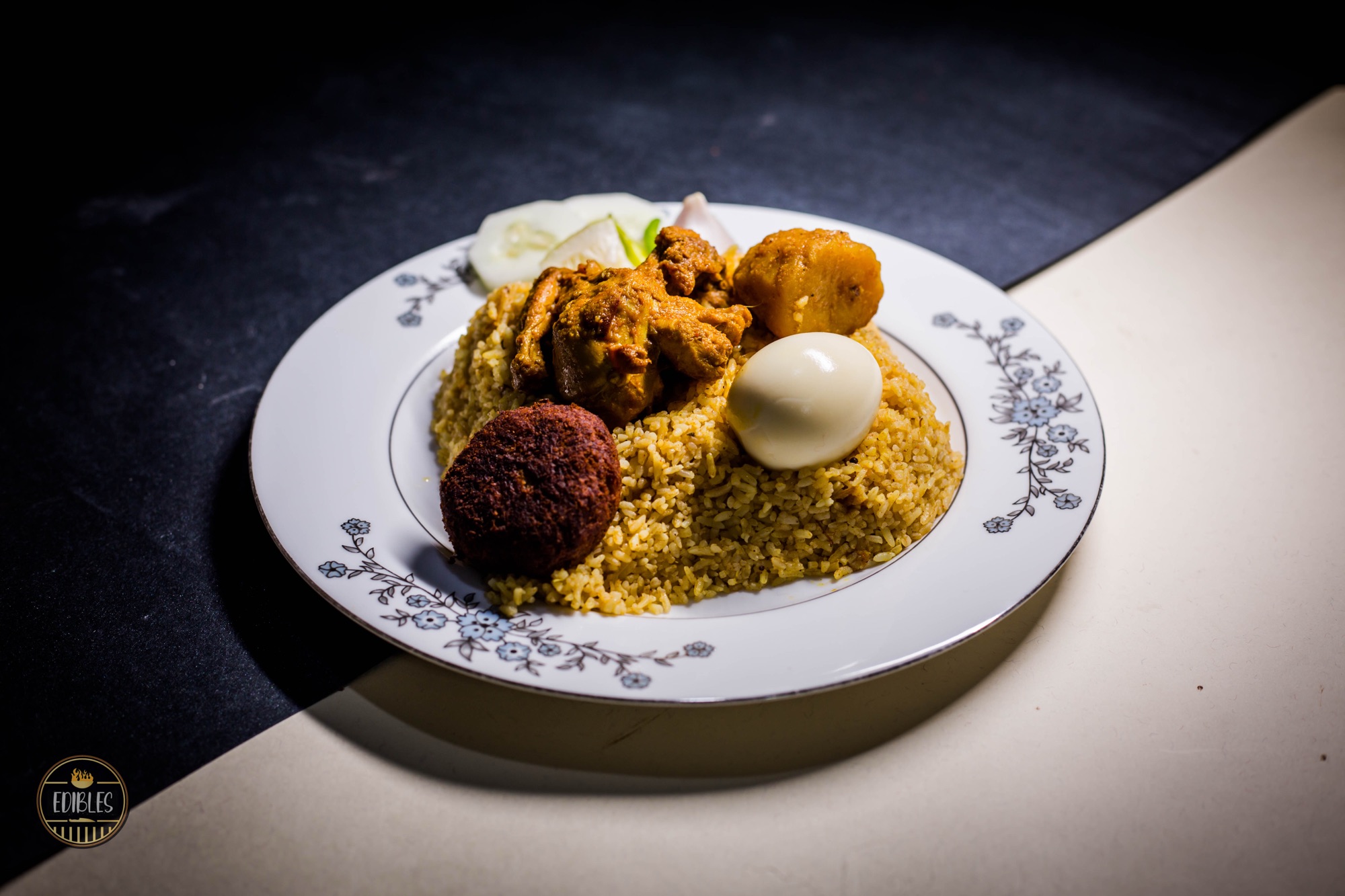 Biryani plated with a meatball and boiled egg on an ornate white dish