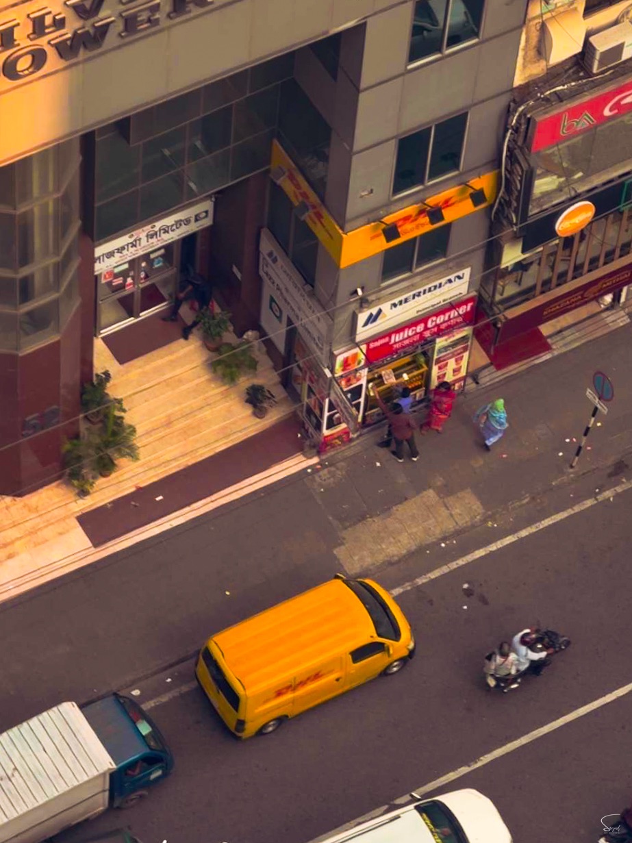 Aerial view of Dhaka street, yellow bus and motorcycles seen from above