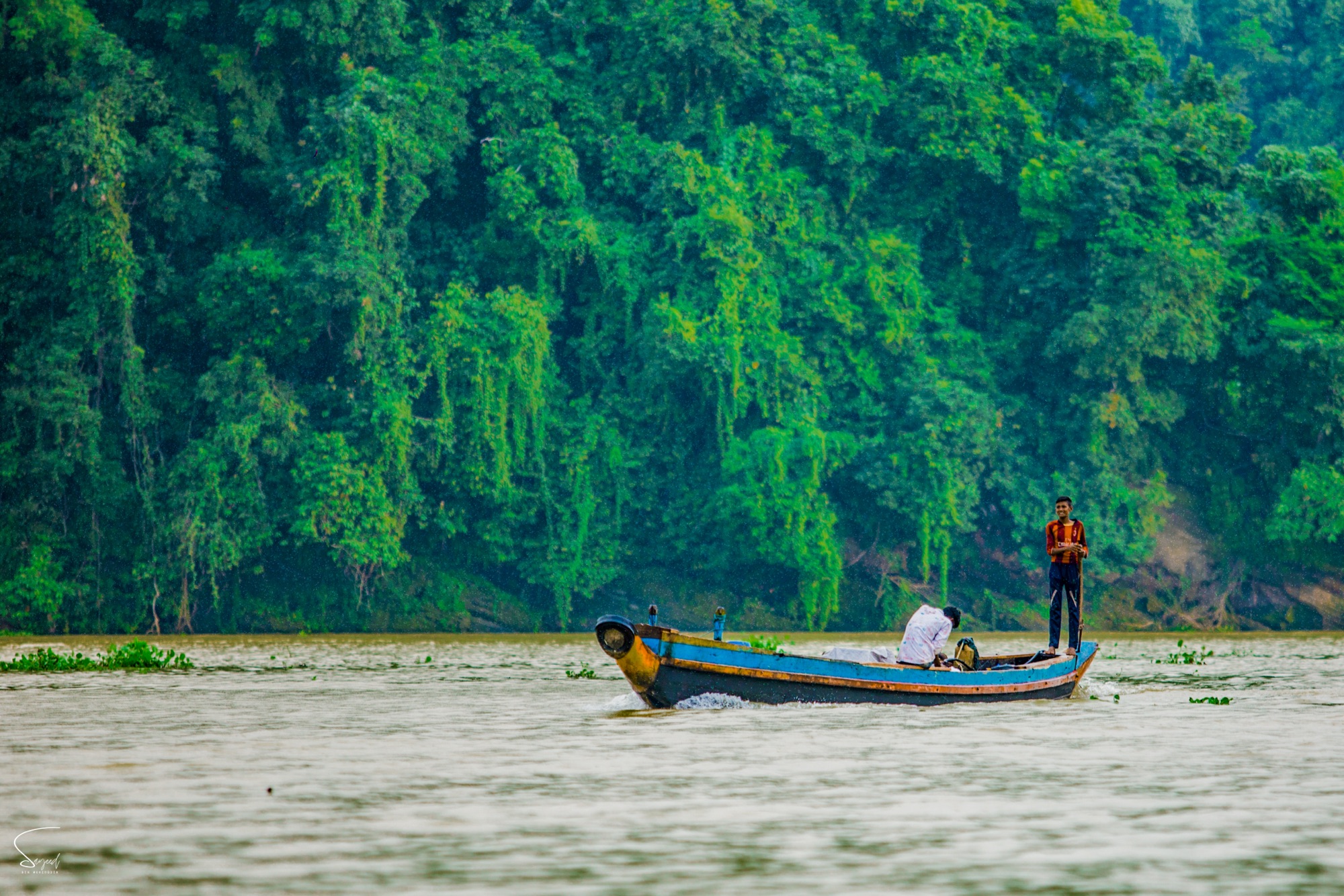 A fishing boat with a boy standing on the water, Rangamati