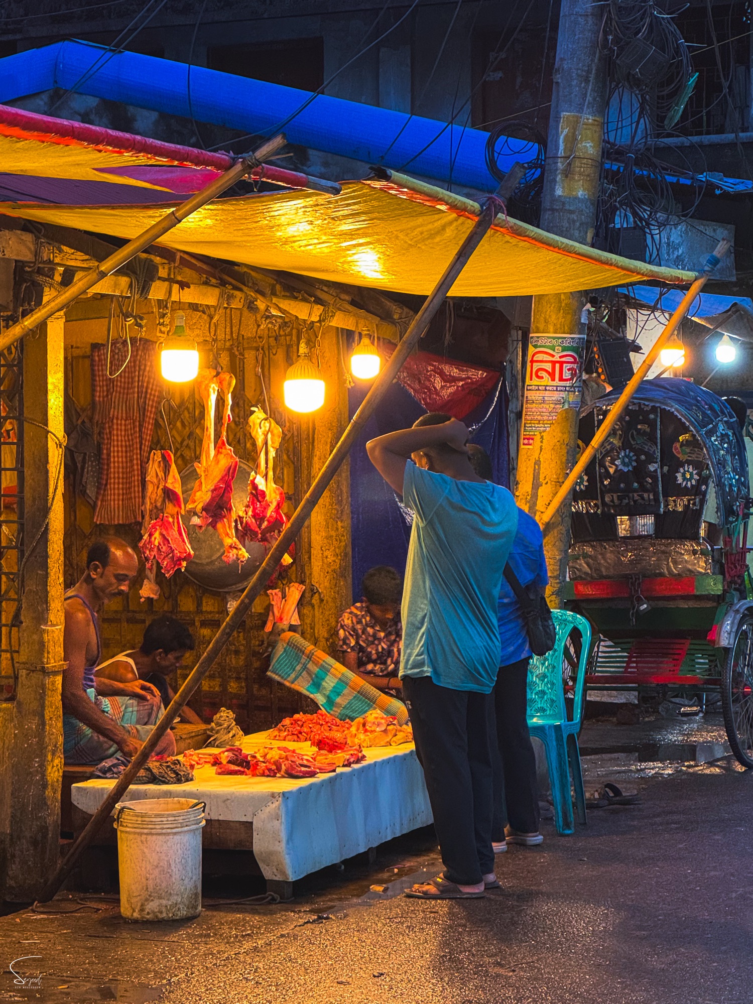 Night market scene, warm golden lights over vendors and goods, Dhaka