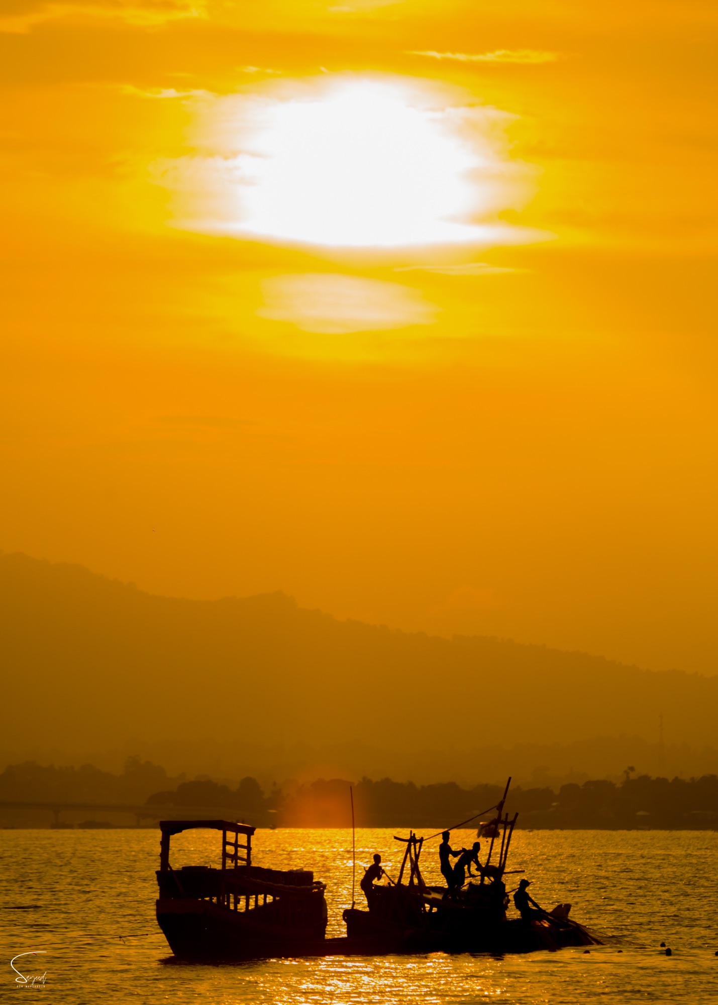 A silhouette of fishermen against the setting sun on the water, Rangamati